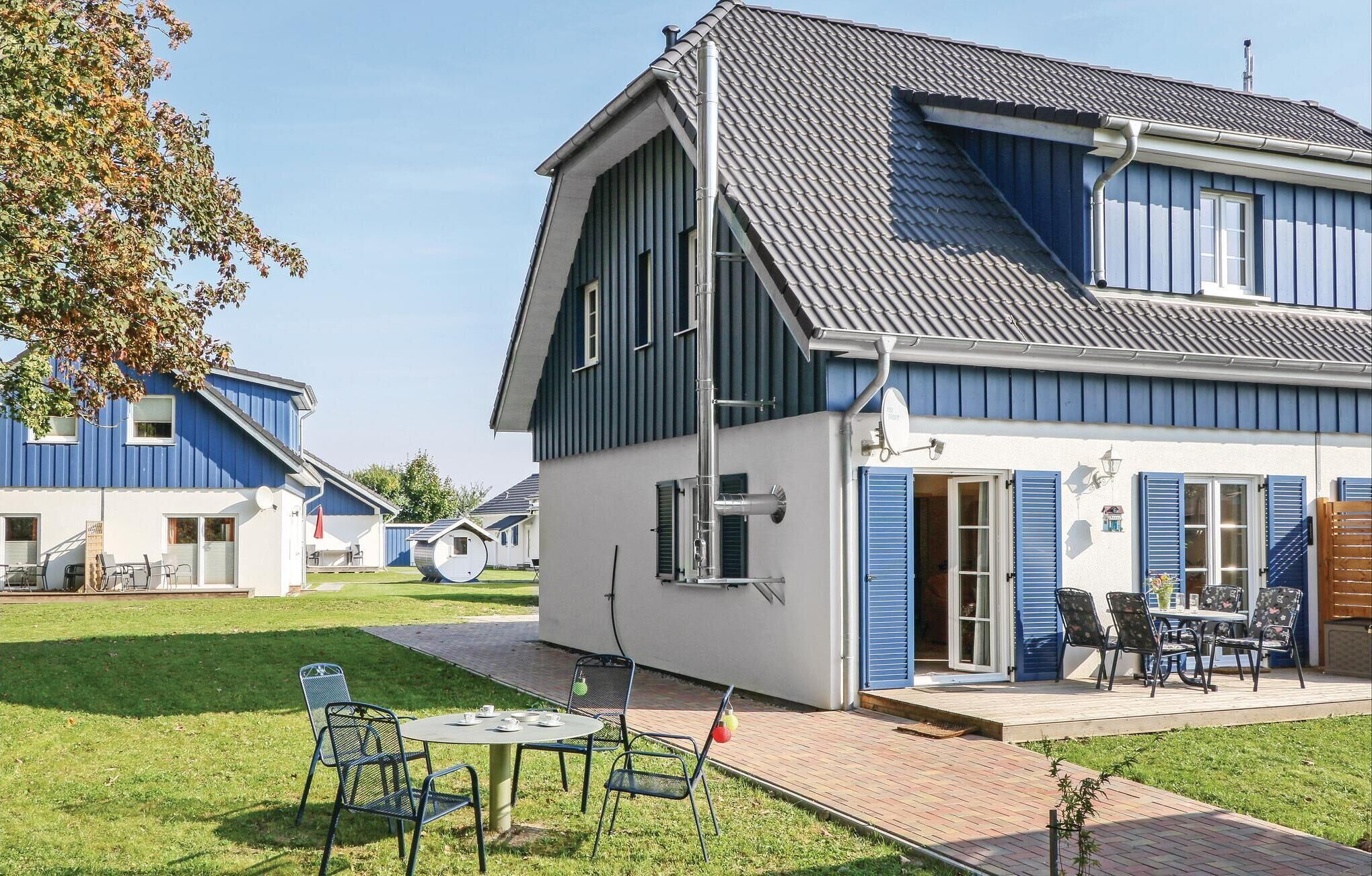 A modern two-story house with a sloped roof, a patio with outdoor furniture, and a small garden area.