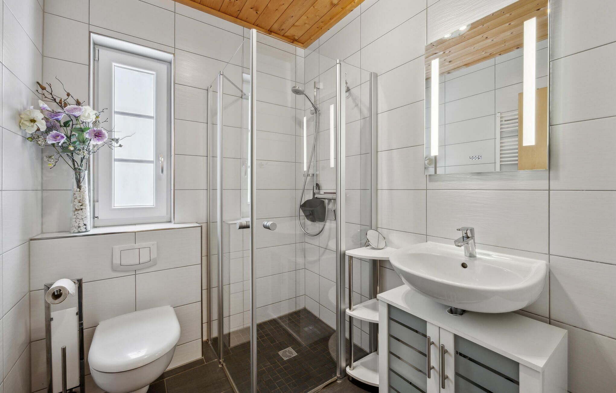 A modern bathroom with a toilet, shower, and sink.