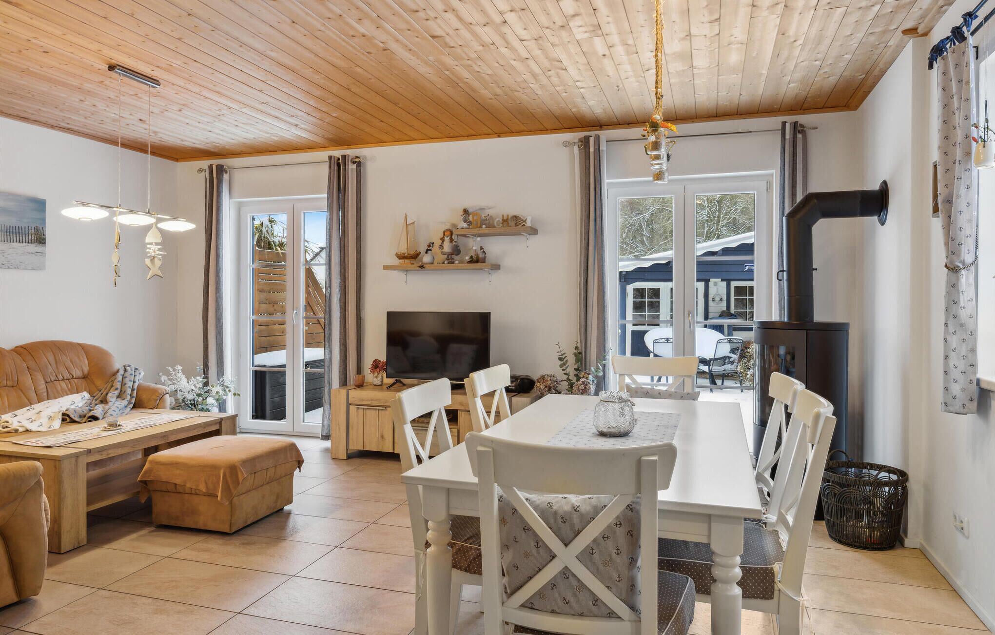 Un accogliente soggiorno con soffitto in legno, televisione, tavolo da pranzo con sedie e camino.