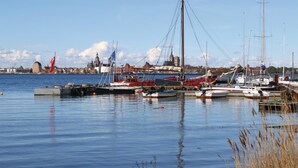 A marina with various boats docked, a cityscape in the background, and a clear sky. - Ferienhaus 44 Altefähr (Altefähr/Rügen)