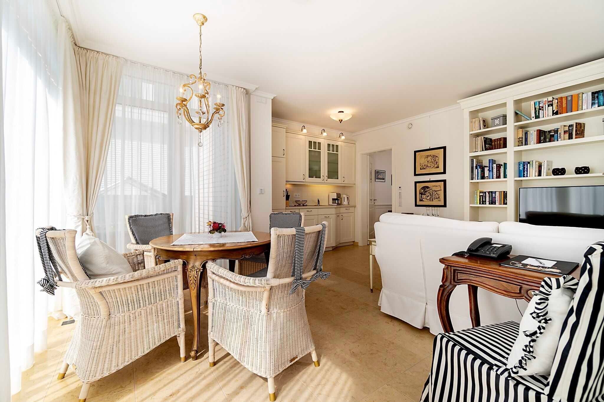 Ein Wohnzimmer mit Rattanmöbeln, einem Esstisch, einem weißen Sofa und einem Bücherregal.