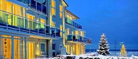 A multi-story hotel with balconies, a snow-covered landscape, and a Christmas tree.