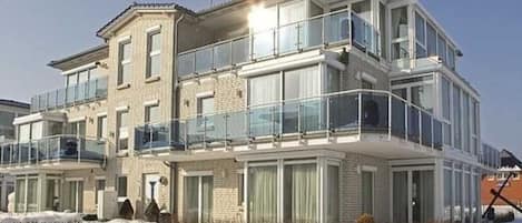 Un edificio residencial de varios pisos con balcones, ventanas grandes y fachada de ladrillo.