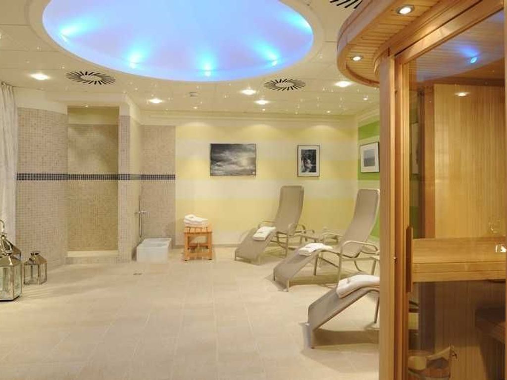 A spa room with a ceiling light, a shower area, and several lounge chairs.
