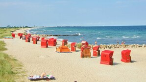 Una playa con sillas rojas y una sombrilla.