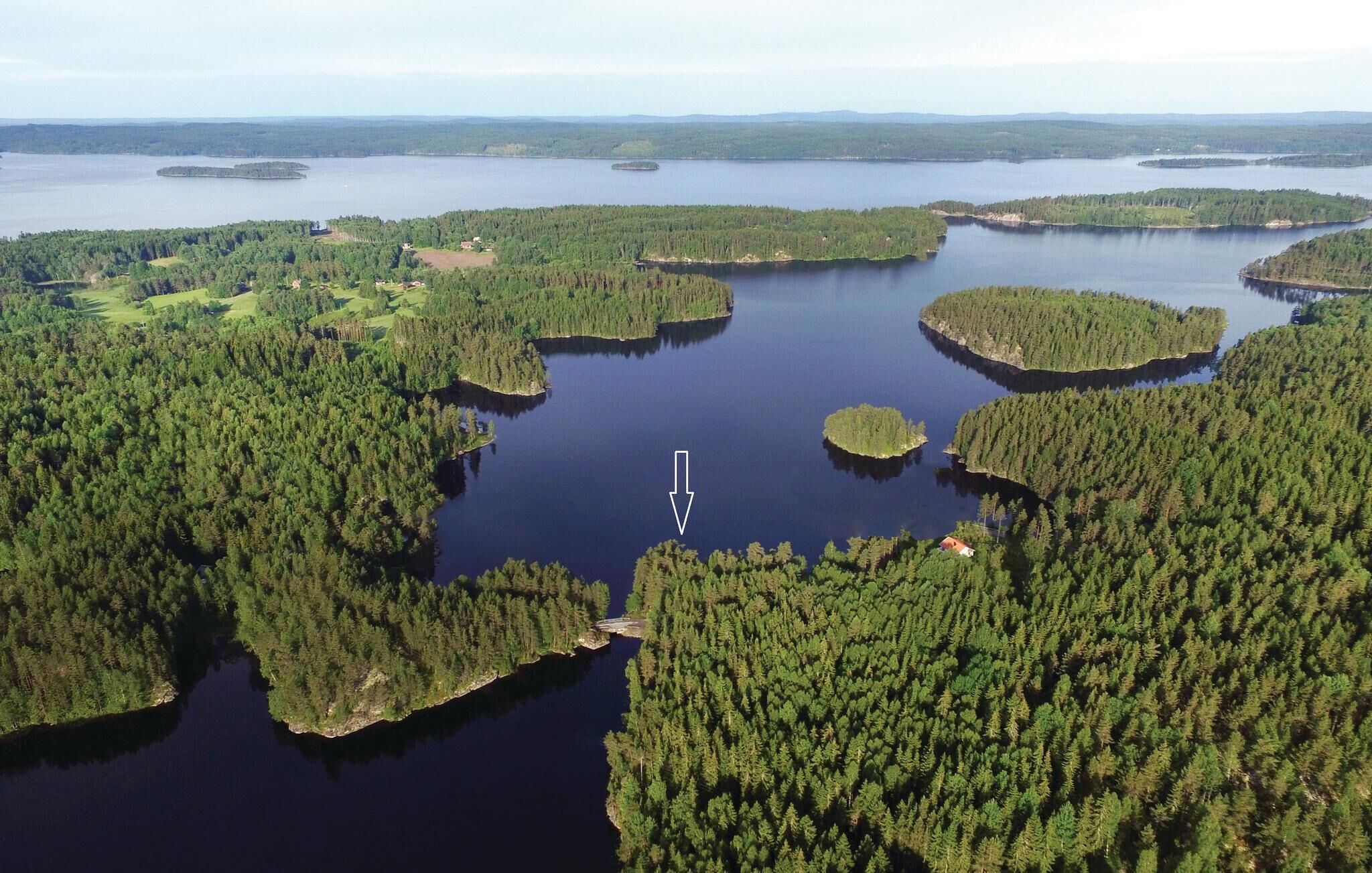 An aerial view of a forested area with multiple lakes and a small island with a dock.
