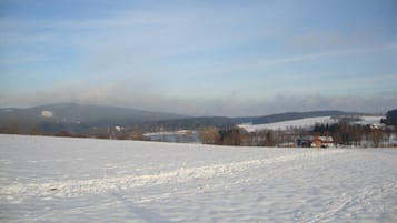 A snowy landscape with a clear sky, distant hills, and a few buildings.