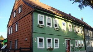 Un edificio de dos pisos con fachada verde, marcos de ventana blancos y puerta roja.