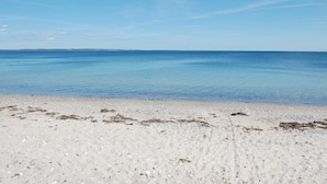 A beach with clear blue water and a sandy shore.