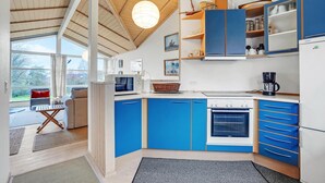A modern kitchen with blue cabinets, a built-in oven, and a coffee maker.