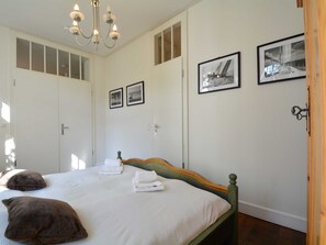 Ein Schlafzimmer mit einem Bett, zwei Kissen, einer Kristallleuchter und drei gerahmten Bildern an der Wand.