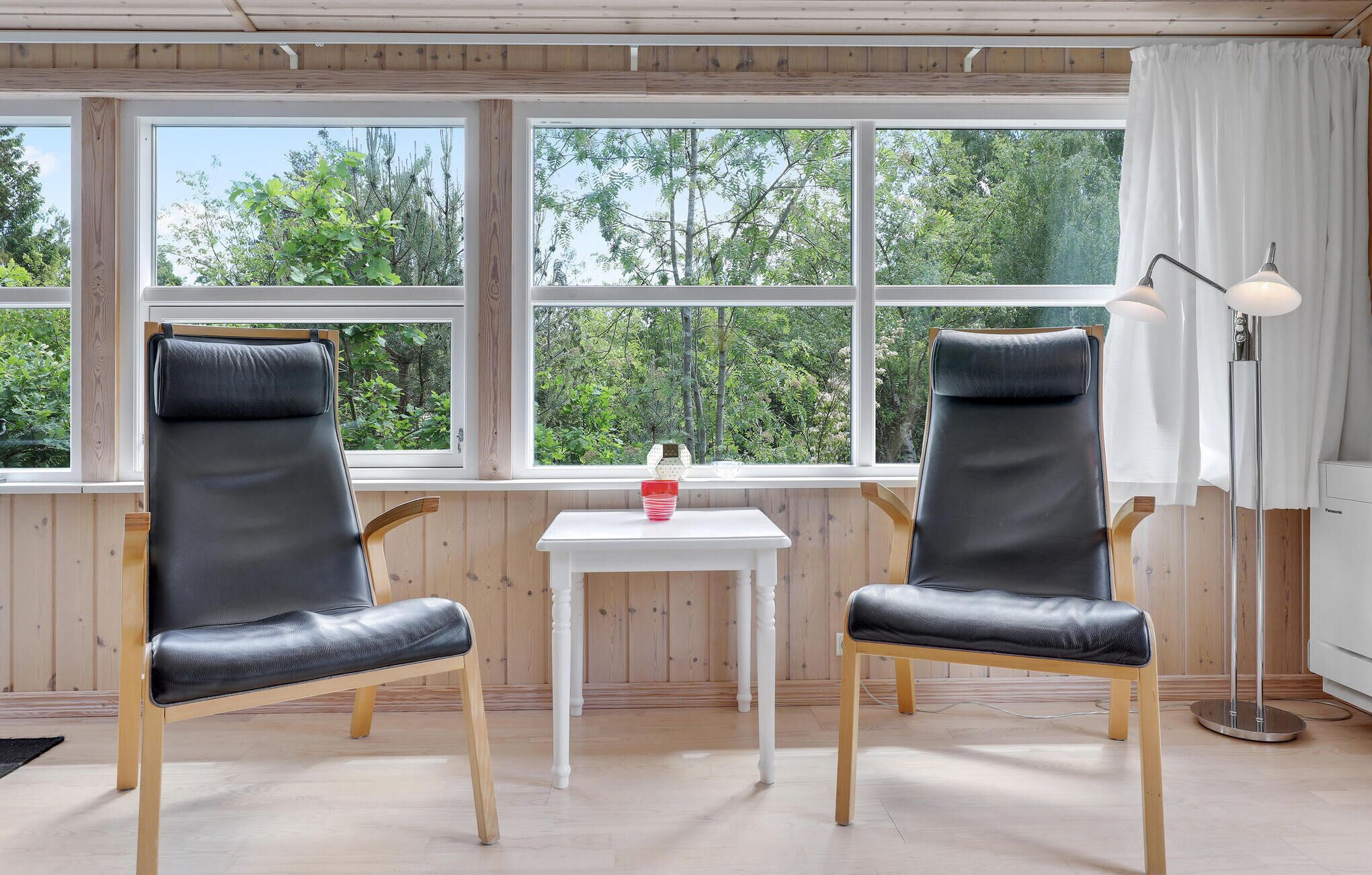 A room with two black leather chairs, a small white table, and a floor lamp.