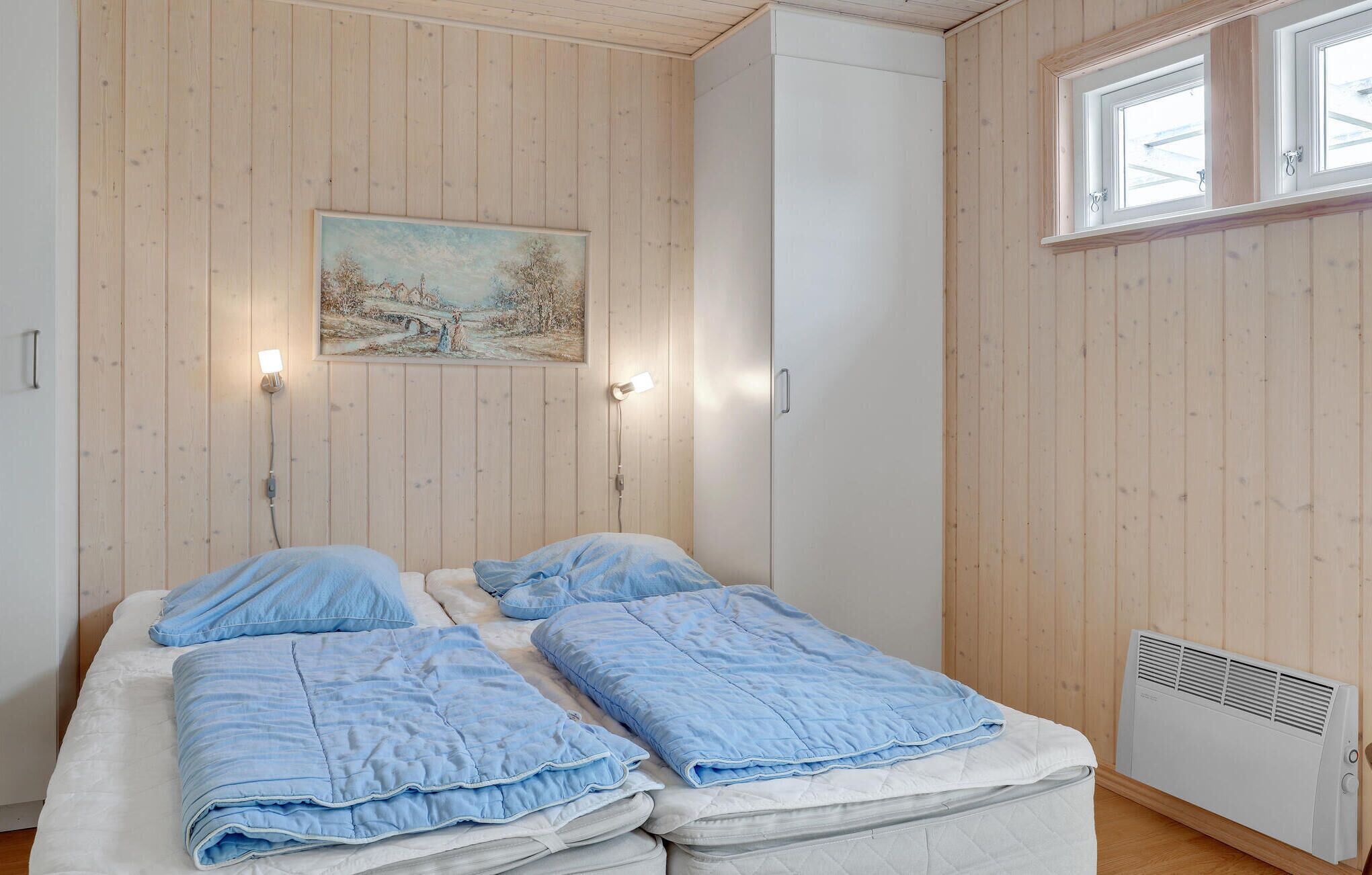 Un dormitorio con dos camas, paredes de madera, un cuadro y una ventana.