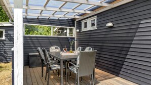 A covered patio with a table and chairs, a small window, and a wall-mounted light fixture. - Cozy home in Nexø with WiFi (Nexø)