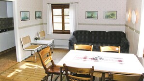 Un coin repas comprenant une table et des chaises, un canapé et une fenêtre avec des rideaux.