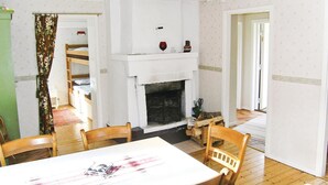 Une pièce avec une cheminée, une table à manger et un escalier menant à une mezzanine.