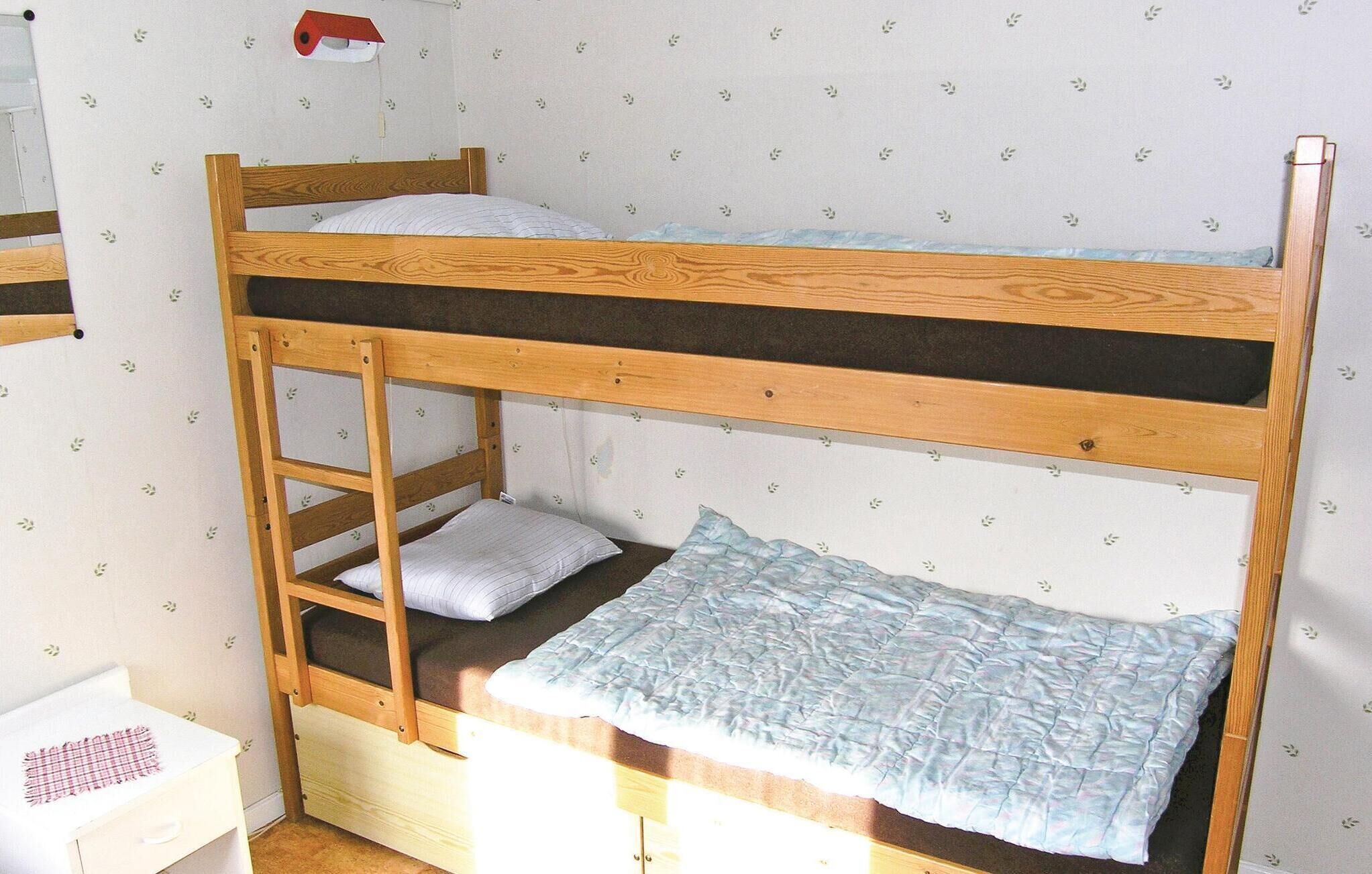 Un lit superposé avec une structure en bois et un lit inférieur doté d’un matelas et d’oreillers.