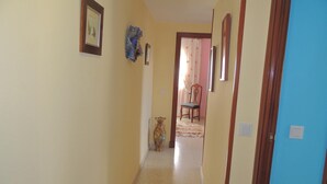 A narrow hallway with a wooden door on the right, a vase on the left, and a chair in the background. - Cozy apartment in Jerez de la Frontera (Jerez de la Frontera)