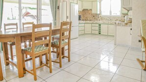 A spacious kitchen with white cabinets, a dining table with chairs, and a view of the outside through large windows. - 3 bedroom lovely home in La Tranche sur Mer (La Tranche sur Mer)