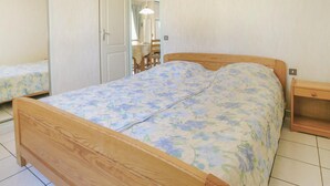 A bedroom with a wooden bed, a bedside table, and a small wooden cabinet. - 3 bedroom lovely home in La Tranche sur Mer (La Tranche sur Mer)