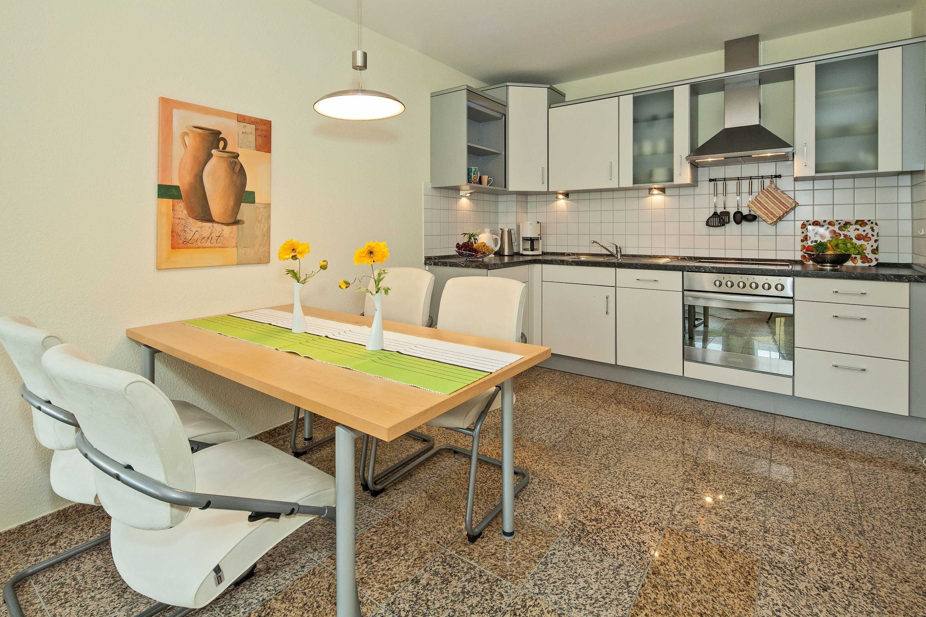 A modern kitchen with white cabinets, a granite countertop, and a stainless steel oven.