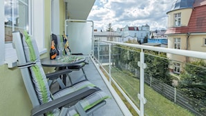 A balcony with two chairs and a table, overlooking a residential area with houses and a church. - Dune Residence C 13 - DR C 13 (Heringsdorf)