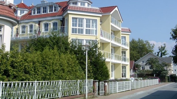 A multi-story building with balconies, a red-tiled roof, and a white fence in front. - Dune Residence C 13 - DR C 13 (Heringsdorf)