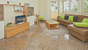 A modern living room with a television, sofa, coffee table, and a small side table. - Dune Residence C 13 - DR C 13 (Heringsdorf)