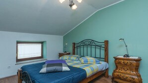 Une chambre à coucher avec un lit, une commode, une fenêtre et une lampe.