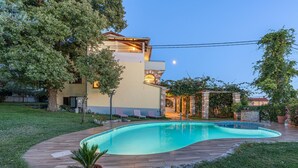Une maison moderne dotée d’une piscine, entourée d’une pelouse bien entretenue et d’arbres.
