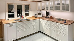 Una cocina moderna con armarios blancos, encimera de madera y horno empotrado.