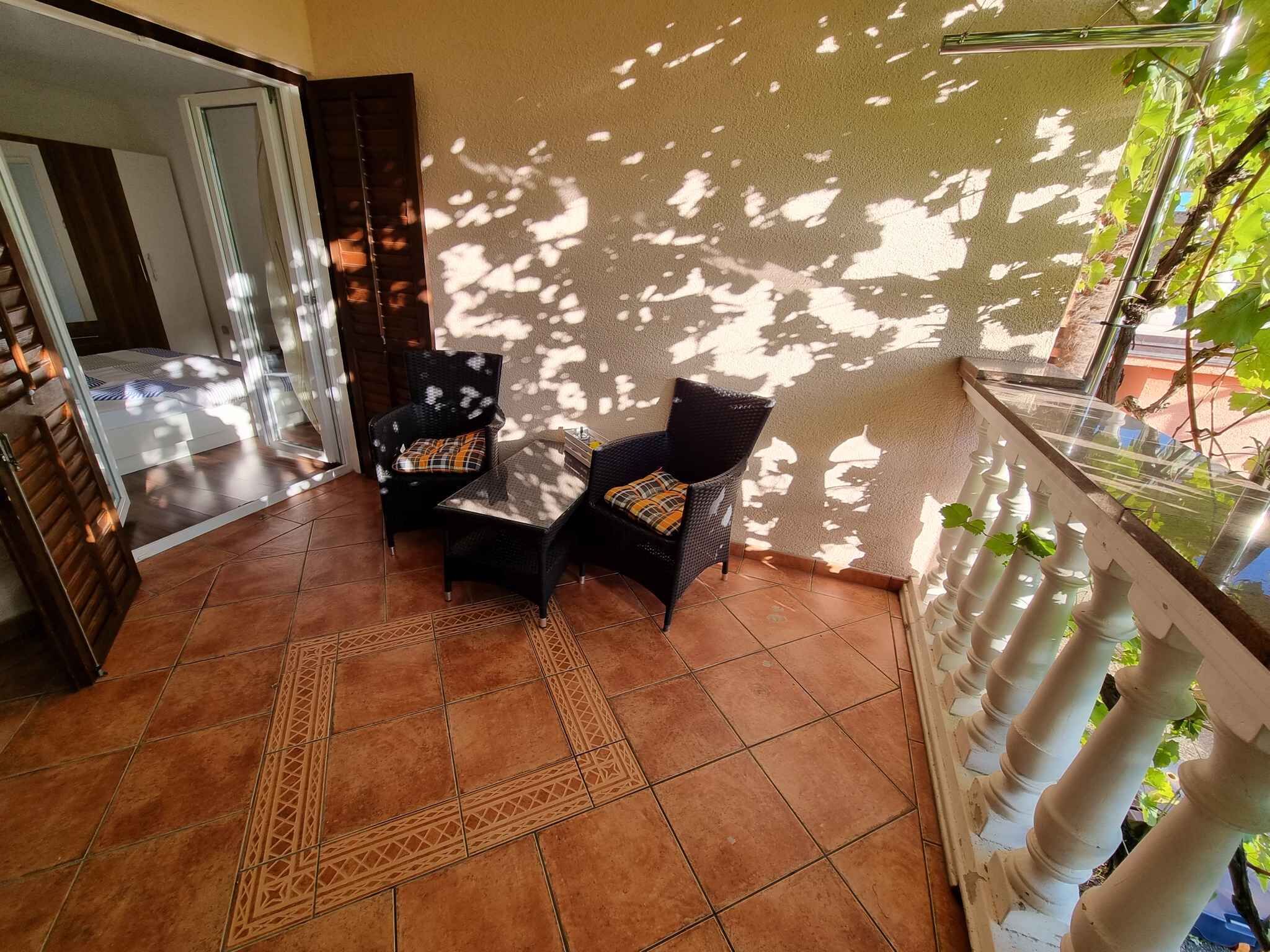 Un espace patio aménagé avec deux fauteuils en osier, une petite table et un tapis décoratif.