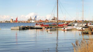 A harbor with various boats docked, a prominent building with a green roof in the background, and calm water reflecting the boats. - Ferienhaus 5 Altefähr (Altefähr/Rügen)