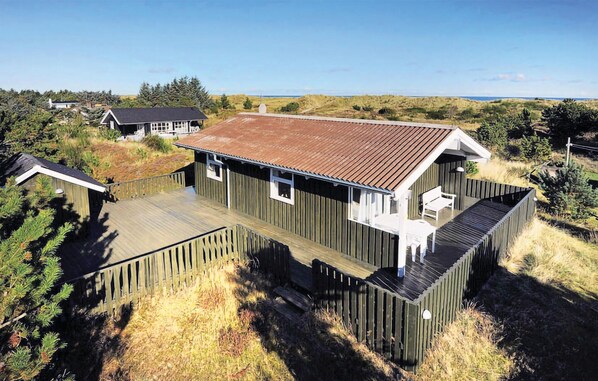 A wooden house with a metal roof, a deck, and a view of the ocean.