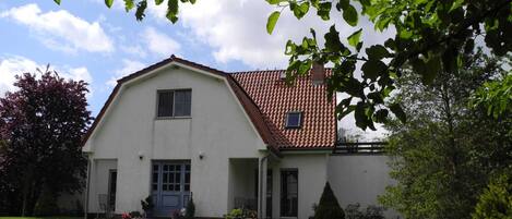 Ein zweistöckiges Haus mit rotem Ziegeldach, einer Veranda und einem gepflegten Rasen.