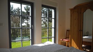 A bedroom with a large window, a wooden wardrobe, and a chair. - Holiday 2 - Holidays from the I Fam. Roman Kurth / TZR (Putbus)