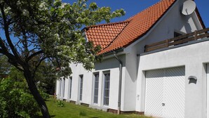 A white building with a red-tiled roof, a garage door, and a satellite dish. - Holiday 2 - Holidays from the I Fam. Roman Kurth / TZR (Putbus)