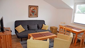 Un salon confortable avec un canapé, une table basse et un coin repas comprenant des chaises et une table.