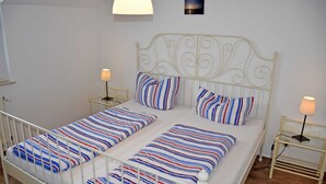 Un lit double avec une literie à rayures, deux tables de chevet avec des lampes et un tableau accroché au mur.