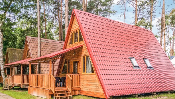 Eine Holzhütte mit rotem Dach, einer Veranda und einem sichtbaren Fenster.