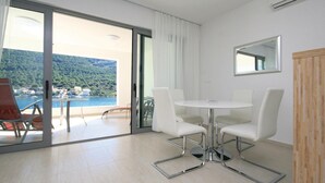 Una habitación moderna con puerta de cristal que da a un balcón con vistas panorámicas a un lago y colinas.