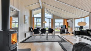 Een ruime woonkamer met een grote open haard, een eettafel met stoelen, een bank en een televisie.