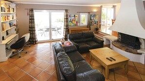 A living room with a sofa, a coffee table, and a fireplace. There is a sliding glass door leading to an outdoor patio. - Cozy home in Caumont sur Durance (Caumont sur Durance)