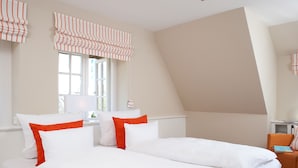 A bedroom with a bed, pillows, a nightstand, a window with curtains, and a chair. - Vis à Vis from A&M - Vis à Vis (Kampen (Sylt))