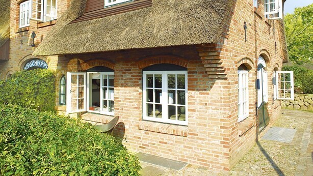 A traditional brick house with a thatched roof, multiple windows, and a small porch area. - Vis à Vis from A&M - Vis à Vis (Kampen (Sylt))