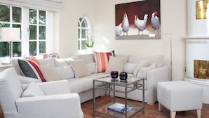 A living room with a sofa, armchairs, a glass coffee table, and a painting of chickens. - Vis à Vis from A&M - Vis à Vis (Kampen (Sylt))
