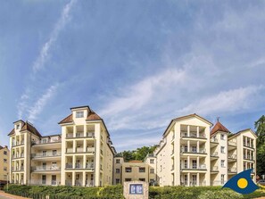 Ett hotell med flera våningar, balkonger, en skylt och en klar himmel.