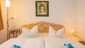 Hotelkamer met een bed, kussens, een nachtkastje, een lamp, een ingelijst foto op de muur en een decoratief object op het bed.