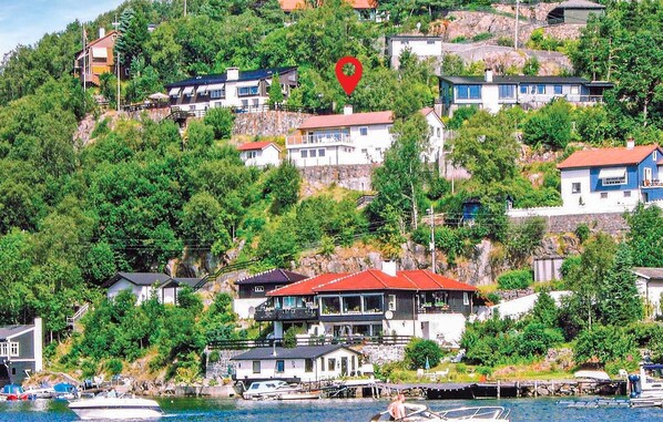 Uma vila costeira com casas numa encosta, uma marina com barcos e um marcador vermelho indicando a localização.