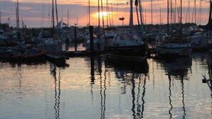 A marina with multiple sailboats docked at sunset. - (166) 2-room apartment - apartment complex Yachthafenresidenz (Kühlungsborn)